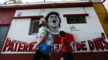 A woman and a boy walk past a mural of Diego Maradona in Buenos Aires, Argentina.