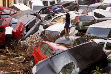 Vecinos observan los autos amontonados luego de ser arrastrados por las inundaciones en Valencia, España.