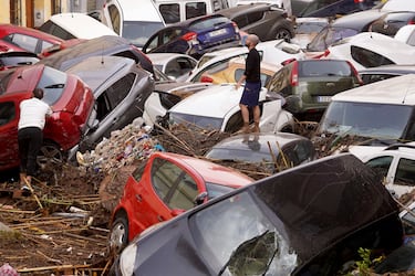 Vecinos observan los autos amontonados luego de ser arrastrados por las inundaciones en Valencia, España.