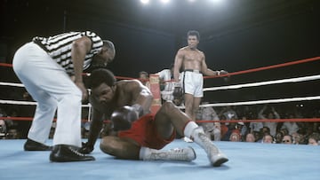 George Foreman intenta levantarse mientras el juez Zack Clayton inicia la cuenta atrás y Muhammad Ali observa a su rival en la lona.