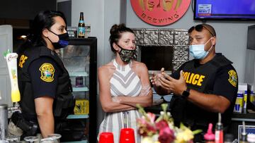 Officers from Florida&#039;s Alcoholic Beverages &amp; Tobacco (ABT) Bureau of Law Enforcement meet with Carrie Hudson (C) the owner of 33 &amp; Melt restaurant during the reopen Florida &quot;maskless&quot; rally and dinner held at her restaurant to prot