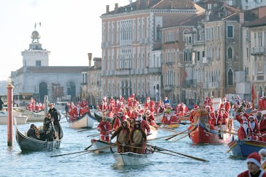 Personas vestidas de Papá Noel reman durantela  regata navideña en el Gran Canal de Venecia.
