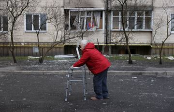 A woman walks in front of a damaged residential building in Kyiv.