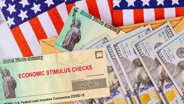 Cheques del Departamento del Tesoro y billetes de cien d&oacute;lares sobre la bandera estadounidense.