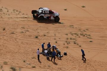 Rodolphe de Palmas de Nomade Racing recibe atención médica mientras Henk Lategan de Toyota Gazoo Racing y el copiloto Brett Cummings pasan al lado. 