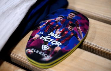Vista detallada de las espinilleras personalizadas de Pau Victor, expuestas en el vestuario del FC Barcelona antes del partido de vuelta de cuartos de final de la UEFA Champions League 2024/25.