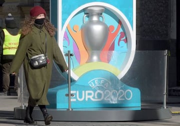 A woman wearing her scarf wrapped around her face walks past the Euro 2020 countdown clock - displaying 449 days left before the event - in downtown Saint Petersburg on March 19, 202