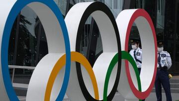 Security guards keep watch next to the Olympic Rings while people take part in a protest against the hosting of the 2020 Tokyo Olympic Games in front of the headquarters building of the Japanese Olympic Committee in Tokyo on May 18, 2021. (Photo by Kazuhi