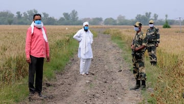 Amritsar (India), 13/04/2020.- Indian Border Security Force (BSF) soldiers (in uniform) stand alert as farmers arrive to inspect their crops across the border fence during the lockdown, near India-Pakistan border, at village Rajatal, about 35km from Amrit