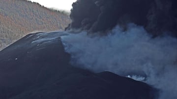 GRAFCAN6192. TAJUYA (LA PALMA), 06/11/2021.-La plaza de Tajuya, en el municipio de El Paso y convertida en un mirador privilegiado de la erupción volcánica de Cumbre Vieja, está hoy más concurrida que en otras ocasiones. El volcán atrae durante el fin de semana a numerosos visitantes que lo observan entre el horror y la admiración. "Es espectacular pero ves esa ladera y sabes lo que hay enterrado y se te rompe el alma" afirma a Efe una mujer, que junto a su familia ha viajado hoy a La Palma desde Tenerife y que refleja el sentir mayoritario de los que se acercan a Tajuya.El día no acompaña. El volcán no para de lanzar humo negro y una ceniza molesta que cubre todo y que los residentes de la zona no paran de limpiar con unos aspiradores que casi se han agotado en la isla. En la imagen, el cono del volcán. EFE/ Elvira Urquijo A.