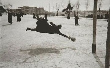 Nos dejó Ramón Masats a los 92 años. El fotógrafo catalán, uno de los más grandes de la fotografía española, es el autor de una de las imágenes más icónicas de la España franquista, la que ilustra estas líneas. La foto muestra a un seminarista intentando detener un chut de otro religioso, en una espectacular estirada con sotana incluida. 