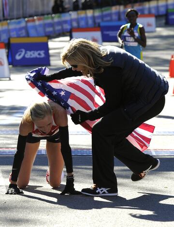 La segunda clasificada de la Maratón de 2010 Shalane Flanagan es cubierta con la bandera estadounidense a su llegada por la Presidenta de la NYRR Mary Wittenberg.