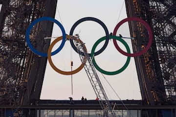 Un grupo de trabajadores, ayudado por una grúa de grandes dimensiones, instala entre el primer y el segundo
piso de la Torre Eiffel, uno de los principales emblemas de la ciudad de París, los anillos olímpicos. Cuando falta menos de un mes para la ceremonia de inauguración de los Juegos, la capital francesa se engalana para la ocasión.
