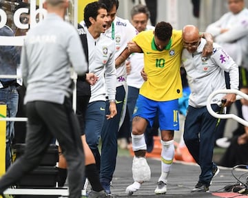 Neymar abandona el estadio ayudado por los médicos de Brasil y con una bolsa de hielo en su tobillo derecho.