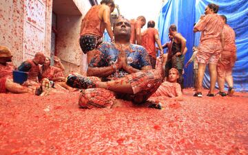 A reveler poses as others enjoy throwing tomatoes at each other, during the annual "Tomatina", tomato fight fiesta, in the village of Bunol, 50 kilometers outside Valencia, Spain, Wednesday, Aug. 30, 2017. At the annual "Tomatina" battle, that has become a major tourist attraction, trucks dumped 160 tons of tomatoes for some 20,000 participants, many from abroad, to throw during the hour-long Wednesday morning festivities. (AP Photo/Alberto Saiz)