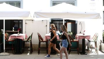 Two women pass by an empty restaurant in the downtown of Zagreb, Croatia.