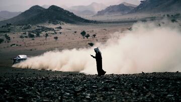 Un hombre mira su teléfono durante el prólogo del Rally Dakar en Bisha, Arabia Saudita.