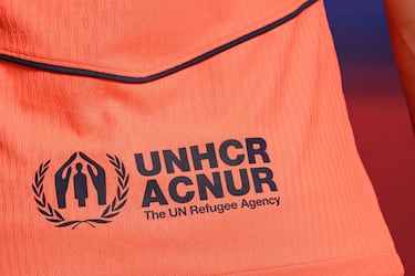 Un llamativo color mango brillante domina en la camiseta –también en los pantalones y las medias– acompañado de varios detalles en azul marino en forma de franjas en el cuello y en la espalda y de filetes que dibujan una forma geométrica en la parte frontal, con el logotipo de Spotify en el centro.