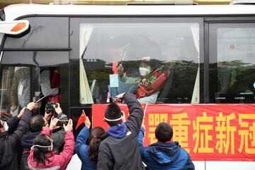 Li Lanjuan, an epidemiologist at the Zhejiang University School of Medicine, waves a Chinese flag from inside a bus as she leaves Wuhan, Hubei province, the epicentre of China's coronavirus disease (COVID-19) outbreak, March 31, 2020