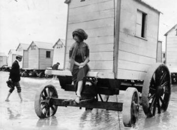 Una mujer en la orilla de la playa sentada en las típicas casetas de verano en 1911.