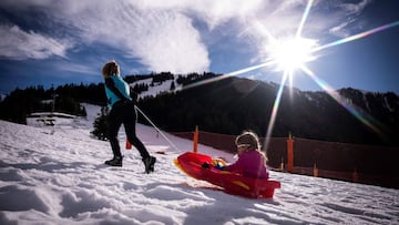 People are pictured as they play with a sled at Le Mourtis mountain resort, on December 16, 2020. - The French government imposed ski resorts to shut their ski lifts over Christmas to stop the spread of the Covid-19 pandemic. (Photo by Lionel BONAVENTURE 