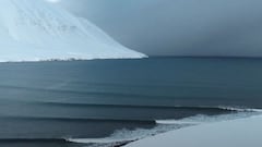 Tres olas perfectas de derechas rompen en el &Aacute;rtico con una monta&ntilde;a completamente nevada de fondo.