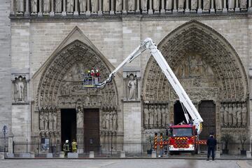 Varios bomberos trabajan en un elevador a la fachada de catedral de Notre Dame