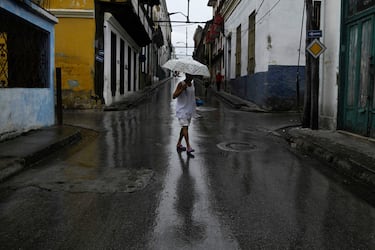 Una mujer con un paraguas camina por una de las calles de Santiago de Cuba antes de la llegada del huracán Melissa.