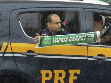 BRA82. CHAPECO (BRASIL), 03/12/2016.- Un miembro de la polic&iacute;a homenajea al club brasile&ntilde;o Chapecoense durante el velorio colectivo de las v&iacute;ctimas del tr&aacute;gico accidente en el que fallecieron 71 personas, entre ellos 19 jugadores, que viajaban para jugar en Medell&iacute;n, noroeste de Colombia, hoy, s&aacute;bado 3 de diciembre de 2016, en la ciudad de Chapec&oacute;, sur de Brasil. La comitiva compuesta por cuatro camiones encargada de trasladar los ata&uacute;des de 50 v&iacute;ctimas del accidente a&eacute;reo recorri&oacute; las calles de Chapec&oacute;, donde se despide a los jugadores y algunas otras v&iacute;ctimas que asistir&iacute;an al partido de ida de la final de la Copa Sudamericana frente al Atl&eacute;tico Nacional colombiano. EFE/Sebasti&atilde;o Moreira