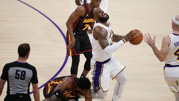Los Angeles Lakers forward LeBron James, center, grimaces as he trips and injures himself over Atlanta Hawks forward Tony Snell, bottom, during the first half of an NBA basketball game Saturday, March 20, 2021, in Los Angeles. (AP Photo/Marcio Jose Sanchez)