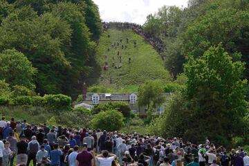 Varios aficionados observan a un grupo de participantes en el Cooper’s Hill Cheese-Rolling and Wake o Festival del queso rodante. Se trata de un evento anual que se celebra en el distrito de Gloucester (Inglaterra) el último lunes de mayo. Los competidores deben atrapar un queso Gloucester arrojado desde una colina inclinada de 182 metros.