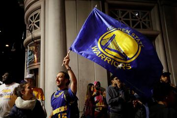 Un aficionado porta una bandera de los Warriors.