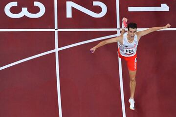 El atleta polaco Kajetan Duszynski cruzando la línea de meta con los brazos en alto celebrando la victoria del equipo polaco en la final de los 4x400 metros mixtos.