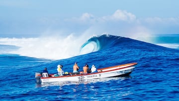 Una ola rompe en Cloudbreak (Islas Fiji) con un barco mirando. 