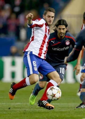 El centrocampista del Atlético de Madrid Koke Resurreción intenta disparar ante el argentino Alejandro Domínguez, de Olympiacos, durante el encuentro de la fase de grupos, grupo A, de la Liga de Campeones que se disputa esta noche en el estadio Vicente Calderón, en Madrid.