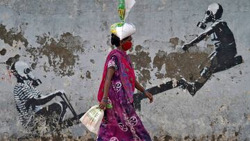 A woman wearing a protective face mask walks past a graffiti, after authorities eased lockdown restrictions that were imposed to slow the spread of the coronavirus disease (COVID-19), in Mumbai, India, June 12, 2020. REUTERS/Hemanshi Kamani     TPX IMAGES