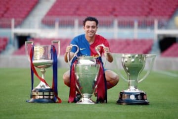 Xavi posando con los trofeos de la Copa del Rey, Champions y Liga logrados en la temporada 08/09