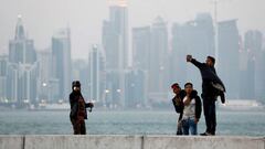 FILE PHOTO: Men take selfies near the sea in front of the skyline of Doha, Qatar, December 19, 2019. REUTERS/Corinna Kern/File Photo