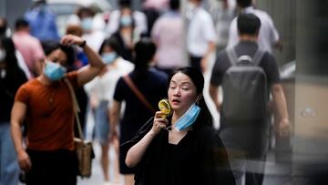 A woman wearing face mask uses a fan as she walks on a street on a hot day, following the coronavirus disease (COVID-19) outbreak in Shanghai, China July 19, 2022. REUTERS/Aly Song