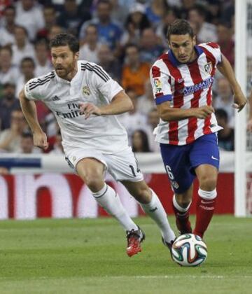 El centrocampista del altético de Madrid Koke Resurrección avanza con el balón ante el centrocampista del Real Madrid Xabi Alonso.