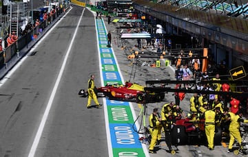 Los mecánicos trabajan en autos en el pit lane.