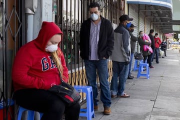 Francisco Montero (center) of Richmond wears a mask while waiting with other in a long line outside of Terra Nova Clinic in the Fruitvale neighborhood of Oakland, Calif.