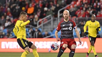 Mar 11, 2023; Toronto, Ontario, CAN; Columbus Crew midfielder Alexandru Matan (20) kicks the ball as Toronto FC midfielder Michael Bradley (4) looks on during the first half in a MLS game at BMO Field. Mandatory Credit: Dan Hamilton-USA TODAY Sports