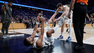 Facundo Campazzo, base del Real Madrid, en el suelo tras una acción frente al Partizán Belgrado en la Euroliga, mientras su compañero David Kramer se ofrece a levantarle.