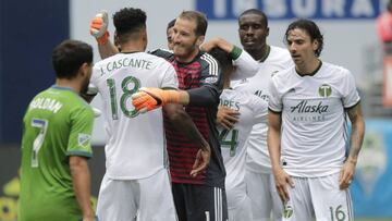 Portland Timbers goalkeeper Jeff Attinella, center, hugs defender Julio Cascante (18) after the Timbers defeated the Seattle Sounders 3-2 in an MLS soccer match Saturday, June 30, 2018, in Seattle. (AP Photo/Ted S. Warren)