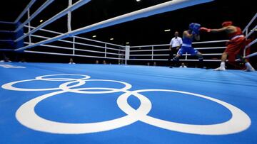 Dos boxeadores en el ring con los anillos olímpicos.