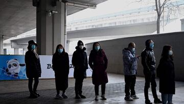 People queue in front of a poster of Bing Dwen Dwen, mascot of the Beijing 2022 Olympic Games, to have their swab samples taken to test for the Covid-19 coronavirus in Beijing on January 24, 2022. (Photo by Noel Celis / AFP)