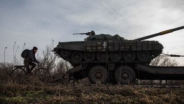 A local resident rides on a bicycle alongside a broken Ukrainian tank to a truck near the frontline town of Bakhmut, amid Russia's attack on Ukraine, in Donetsk region, Ukraine January 20, 2023. REUTERS/Oleksandr Ratushniak