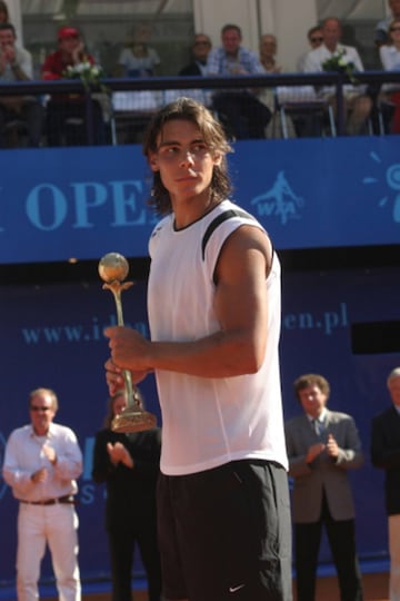 Toda trayectoria legendaria tiene un comienzo, y la de Rafa no iba a ser menos. Todo arrancó en 2004 en el torneo de Sopot (Polonia), donde un imberbe Nadal conquistó el primer título de su carrera ante José Acasuso, lo que le sirvió para obtener el primero de sus infinitos récords: se convirtió en el tenista más joven de la historia en ganar un título en tierra batida. Es más, con 18 años y 2 meses superó el récord histórico de precocidad de Lleyton Hewitt de ganar un trofeo en cualquier superficie. Al término de la final recibió un homenaje sobre la arcilla polaca, el primero de muchos.
