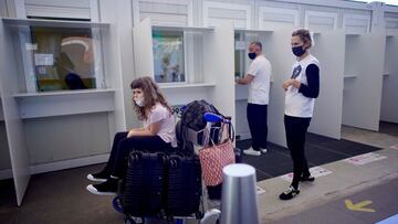 A family waits to do a COVID-19 saliva test after arriving to Argentina from Miami at Ezeiza International airport on the outskirts of Buenos Aires, Monday, Dec. 21, 2020. The last flight from Britain arrived Monday morning after authorities suspended commercial flights to and from Britain amid concerns of new strains of the coronavirus. (AP Photo/Victor R. Caivano)